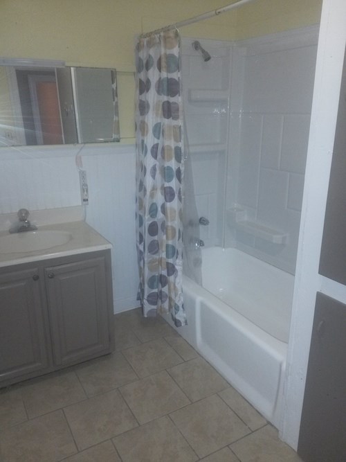 A bathroom with a shower curtain and a sink.