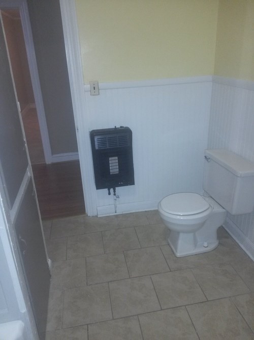 A white toilet sits in a bathroom next to a white radiator.