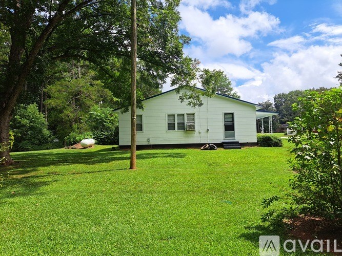 A white house with a green lawn in front.