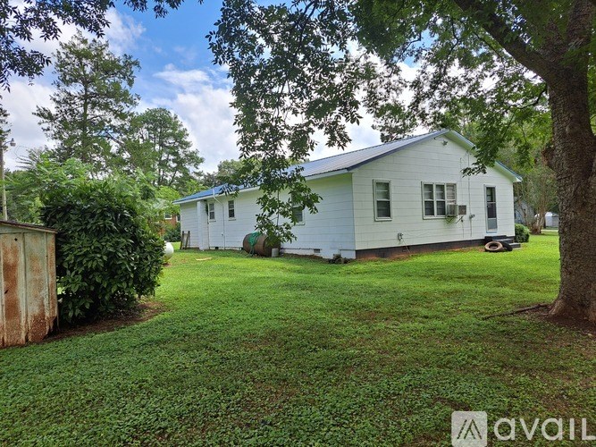 A white house with a green lawn and trees in the background.