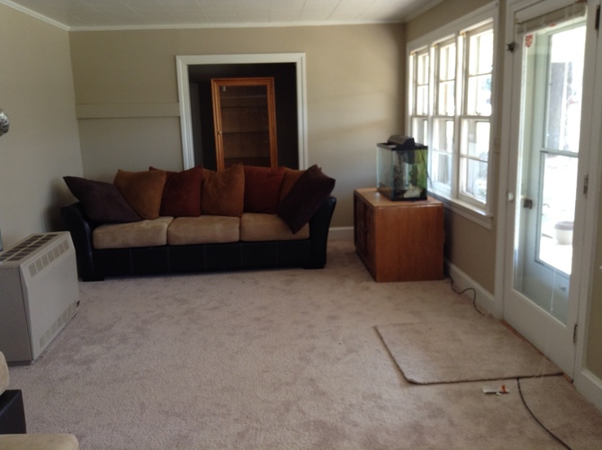 A living room with a couch, a fish tank, and a window.