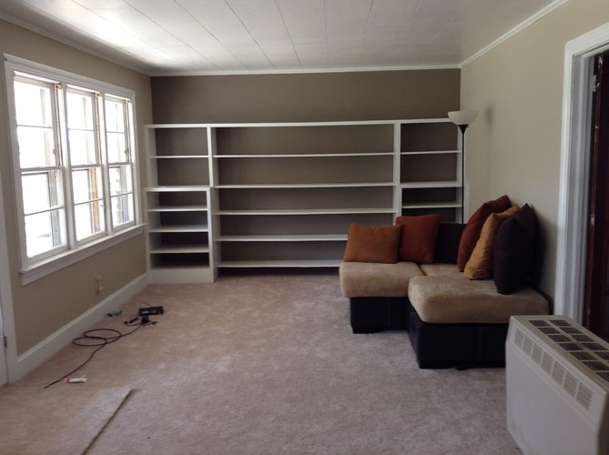 A room with a window, a couch, and a shelf.