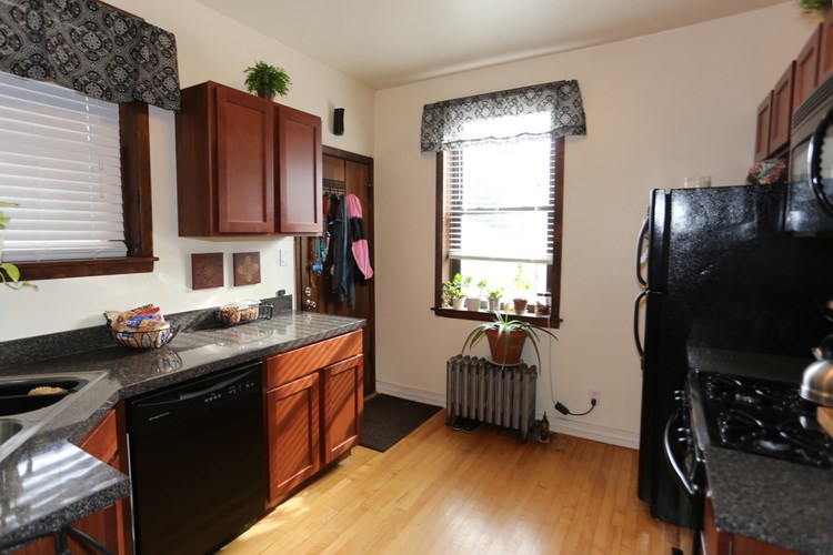A kitchen with black appliances and wooden cabinets.