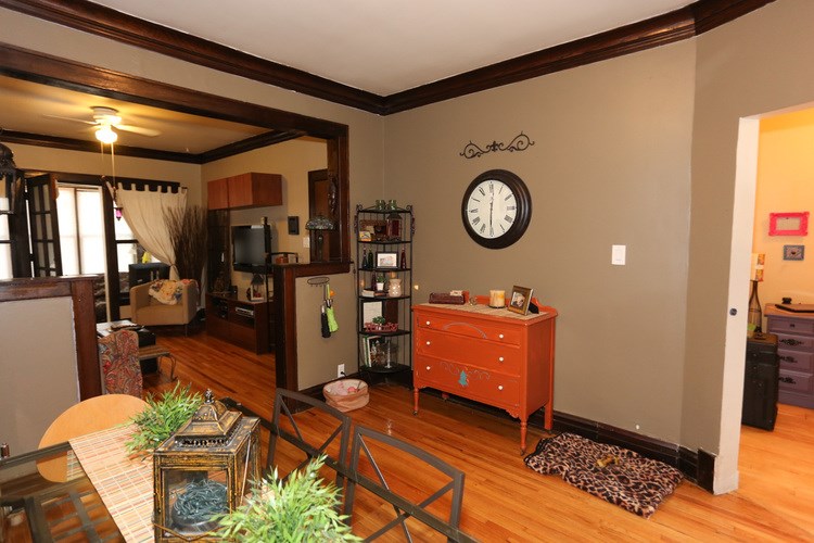 A room with a clock on the wall and a dresser in the corner.