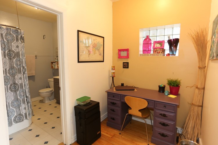 A bathroom with a toilet, a desk, and a chair.