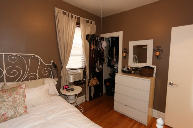 A bedroom with a white bed and a white dresser with a mirror above it.
