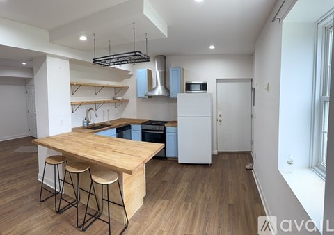 A kitchen with a wooden counter and bar stools.