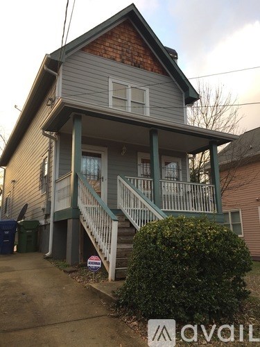A house with a grey siding and a red brick chimney is for sale.