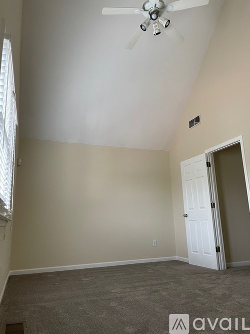 A room with a ceiling fan and a door.