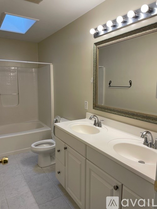 A bathroom with a toilet, sink, and mirror.