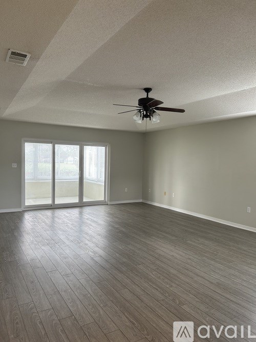 A spacious room with a ceiling fan and sliding glass doors.