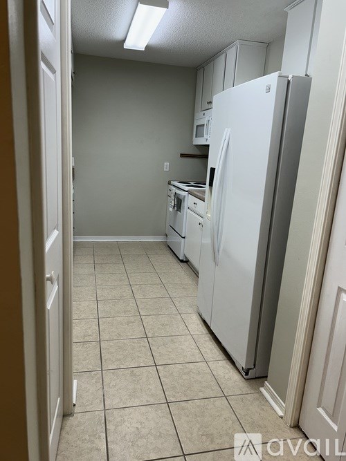 A kitchen with a white refrigerator and white cabinets.