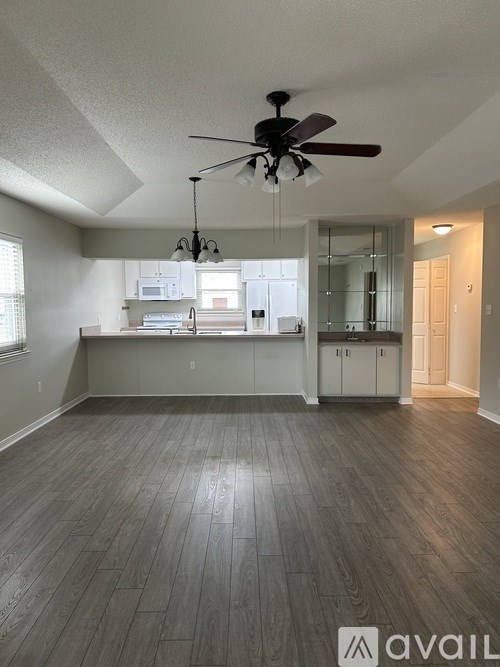 A spacious room with a ceiling fan and wooden flooring.