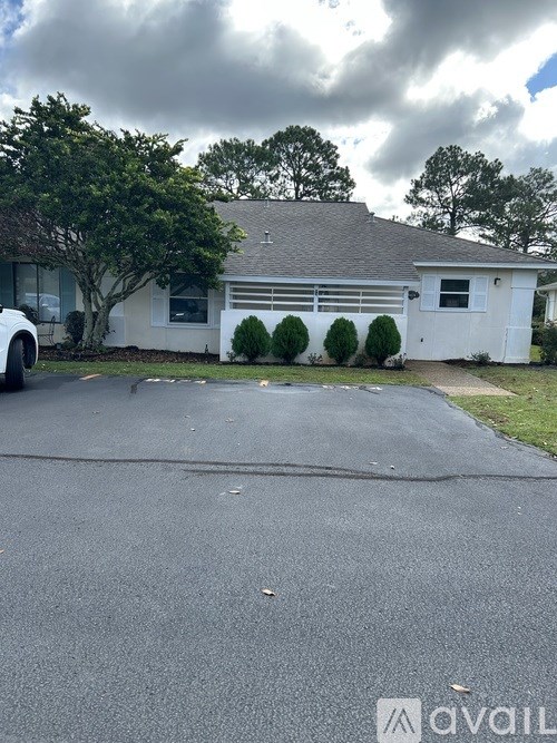 A white house with a grey roof and a white car parked in front.