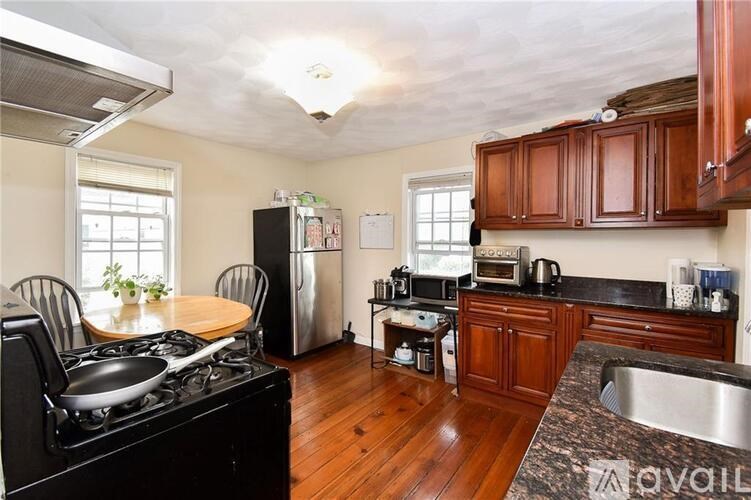 A kitchen with a black stove top oven and wooden floors.