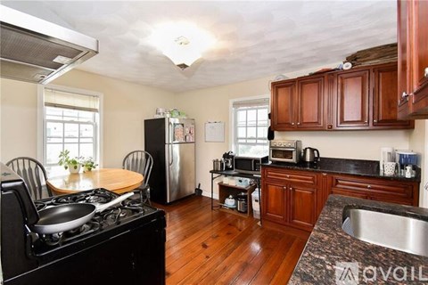 A kitchen with a black stove top oven and wooden floors.