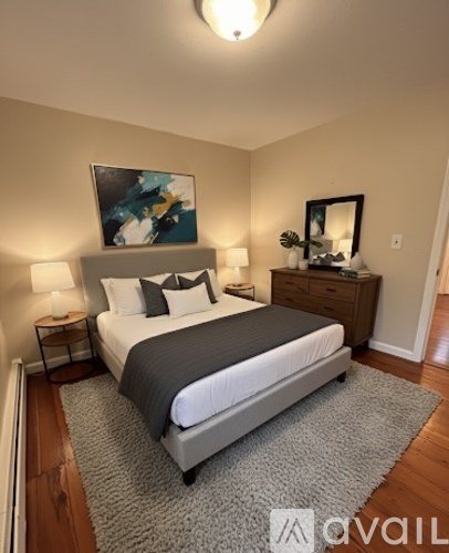 A bedroom with a large bed, a nightstand with a lamp, and a painting on the wall.