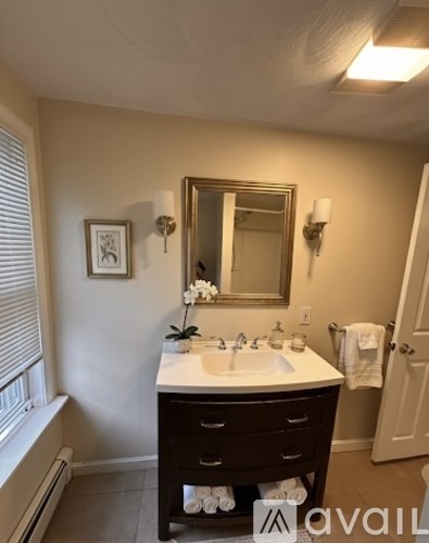 A bathroom with a sink, mirror, and a window.