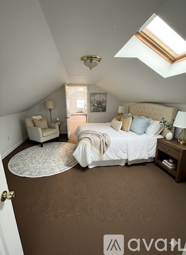 A bedroom with a bed, a chair, and a rug.