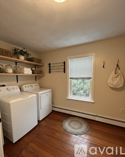A laundry room with a washer and dryer, a window, and a hanging rack.