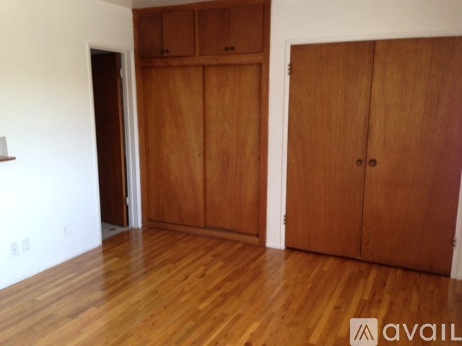 A room with wooden floors and two wooden doors.