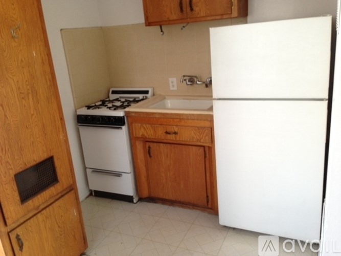 A small kitchen with a white refrigerator, a white stove, and wooden cabinets.