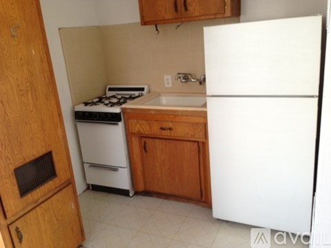 A small kitchen with a white refrigerator, a white stove, and wooden cabinets.