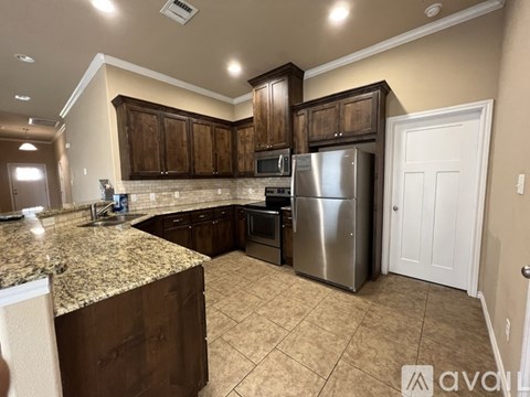 A kitchen with brown cabinets and a granite countertop.