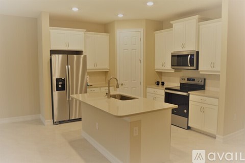 A kitchen with white cabinets and a stainless steel refrigerator.