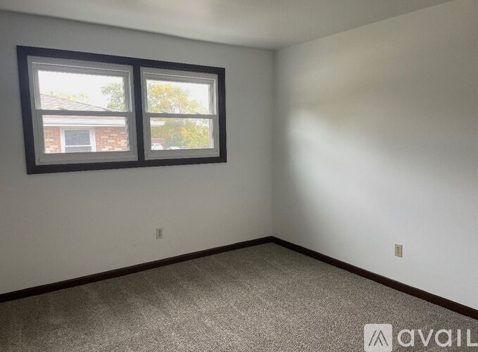A room with two windows and carpeted floor.