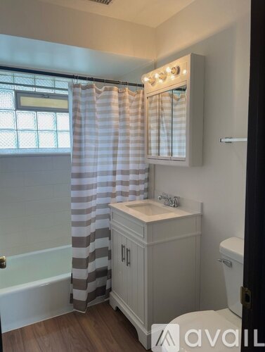 A bathroom with a striped shower curtain and wooden floors.
