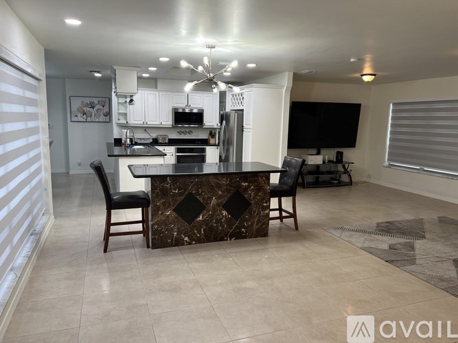 A modern kitchen with a marble island and a television in the background.