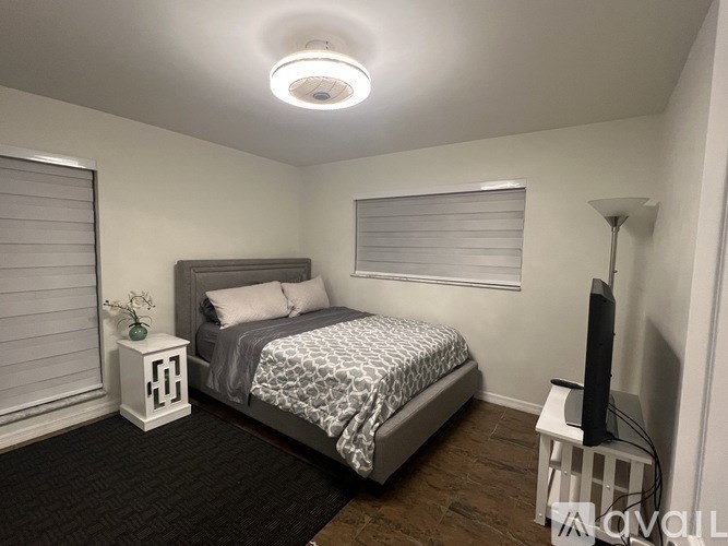 A bedroom with a bed, nightstand, and a television.