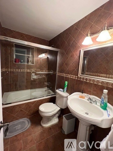 A bathroom with brown tiles and a white sink.