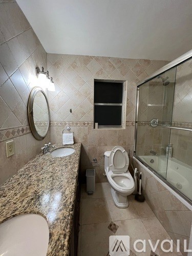 A bathroom with a granite countertop and a glass shower area.