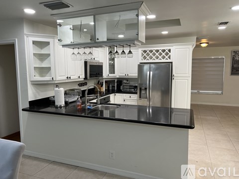 A modern kitchen with white cabinets and black countertops.