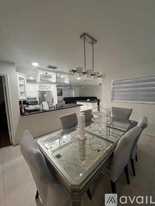 A modern dining room with a glass table and chairs.