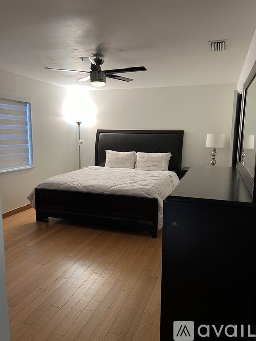 A bedroom with a bed, a ceiling fan, and a wooden floor.