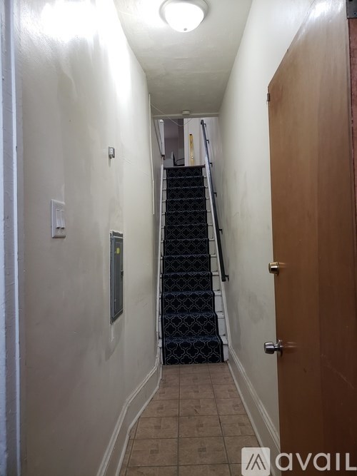 A hallway with a staircase and a door on the right.