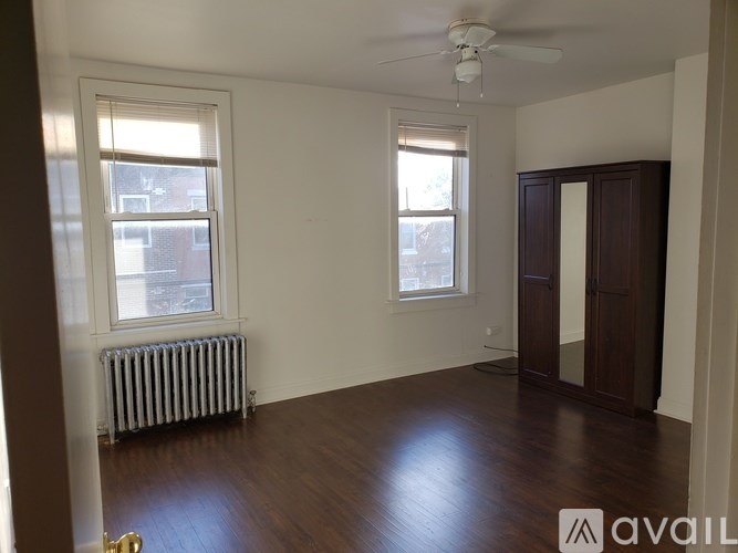 A room with a ceiling fan and two windows.