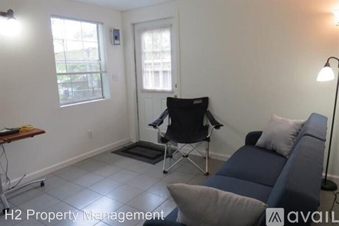 A living room with a blue couch, a chair, and a lamp.