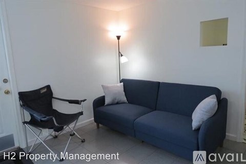 A blue couch with a white pillow and a black chair in a room.