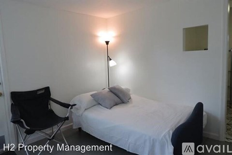 A bedroom with a bed, chair, and lamp.