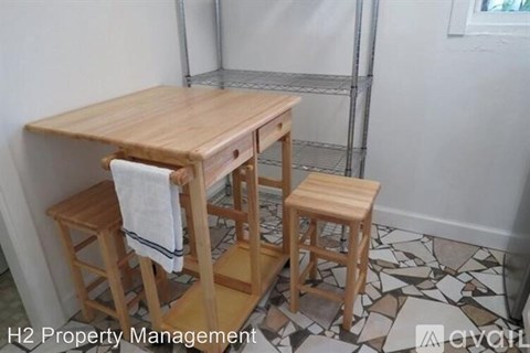A wooden table with two chairs and a towel hanging on the back of one chair.