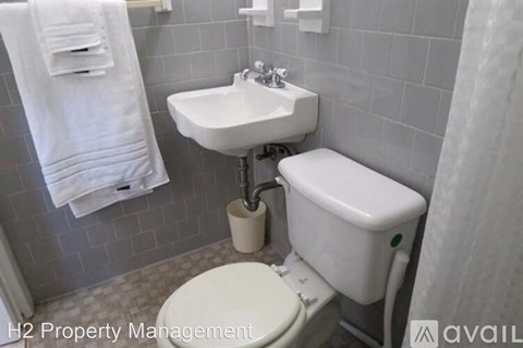 A white toilet with a white sink and toilet paper holder in a bathroom.