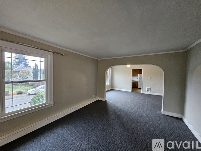 A room with a carpeted floor and a large window overlooking a street.
