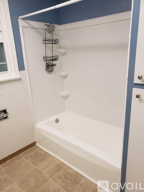 A white bathtub with a shower head and a glass door.