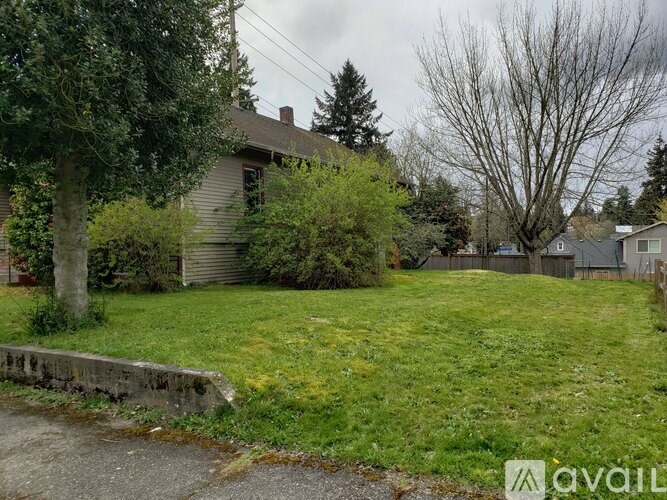 A house with a green lawn and a tree in front of it.