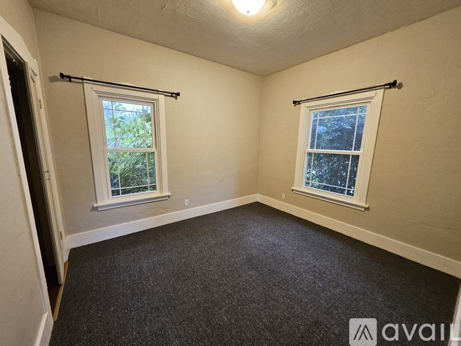A room with two windows and a carpeted floor.