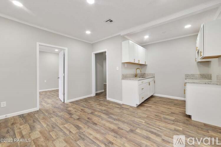 A kitchen area with white cabinets and a wooden floor.